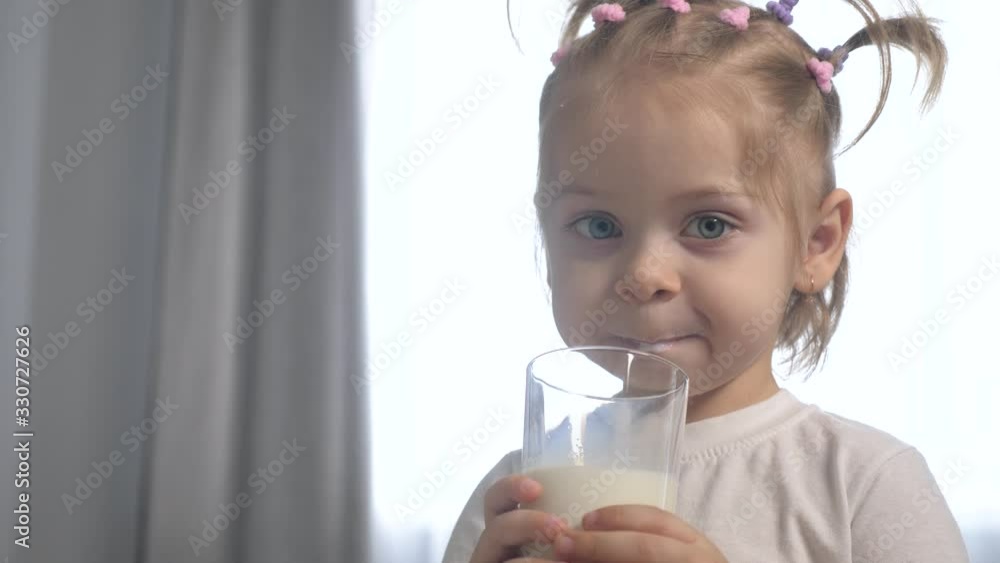 little lifestyle girl drinks milk. child drinks milk from a glass glass indoors morning breakfast little lifestyle girl drinks milk. child drinks milk from a glass glass indoors morning breakfast