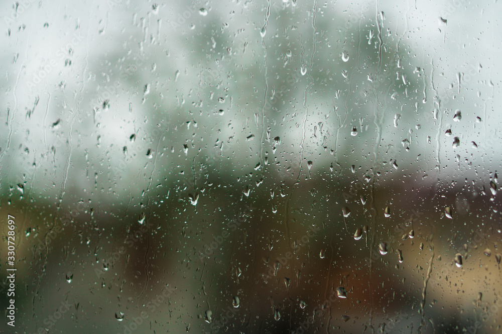 Window overlooking a rainy street. Gloomy evening weather with a view of the road. Drops on glass and bokeh from cars. Stock background for design Window overlooking a rainy street. Gloomy evening weather with a view of the road. Drops on glass and bokeh from cars. Stock background for design