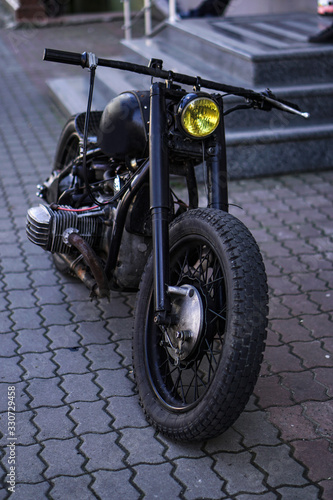 An old home-made motorcycle stands on the street. Punk and biker theme. Stock background