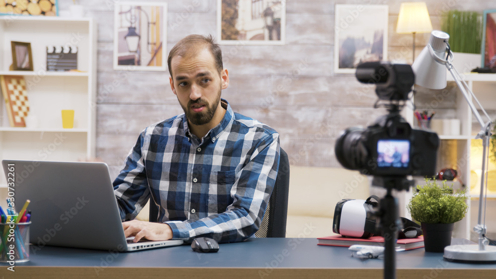 Fototapeta premium Famous young vlogger typing on laptop while talking