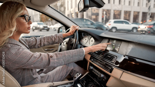 Smart parking. Side view of focused business woman using parking assist system while driving a car