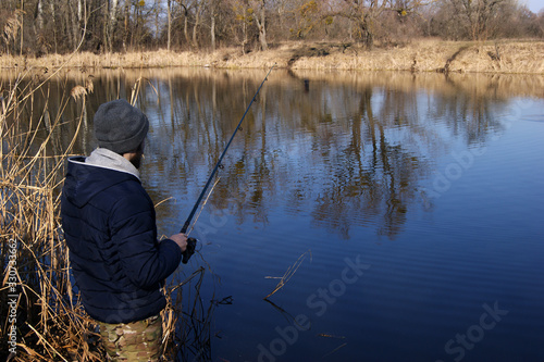 Fishing rod in the hands of a fisherman on the lake.