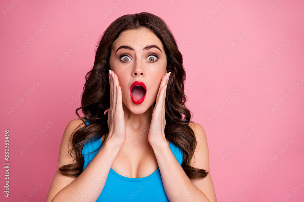 Closeup photo of pretty curly lady open mouth arms on cheeks listen awful shocking news eyes full fear wear casual blue tank-top isolated pink bright color background Closeup photo of pretty curly lady open mouth arms on cheeks listen awful shocking news eyes full fear wear casual blue tank-top isolated pink bright color background