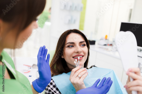 Tableau sur toile Girl chooses color of veneers at the dentist office