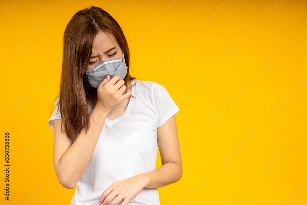Asian woman is coughing or sneezing wearing hygienic mask to protect virus, COVID 19 or Colona Virus infection and dust PM 2.5 pollution isolate on yellow background Asian woman is coughing or sneezing wearing hygienic mask to protect virus, COVID 19 or Colona Virus infection and dust PM 2.5 pollution isolate on yellow background