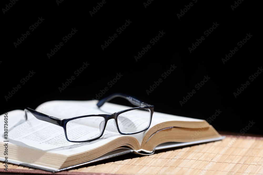 open book and black glasses isolated on a black background open book and black glasses isolated on a black background