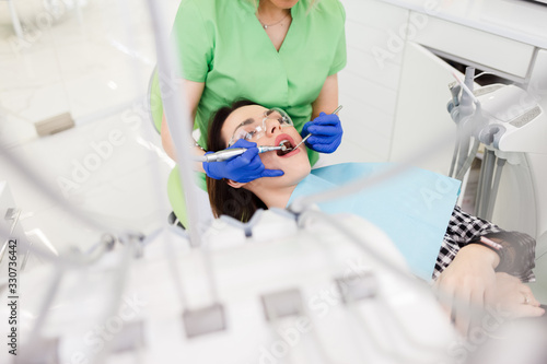 Young beautiful woman treats teeth at the dentist cabinet. Dental treatment process
