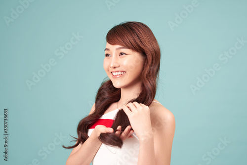 Asian woman smiling with long hair, isolated over blue background.