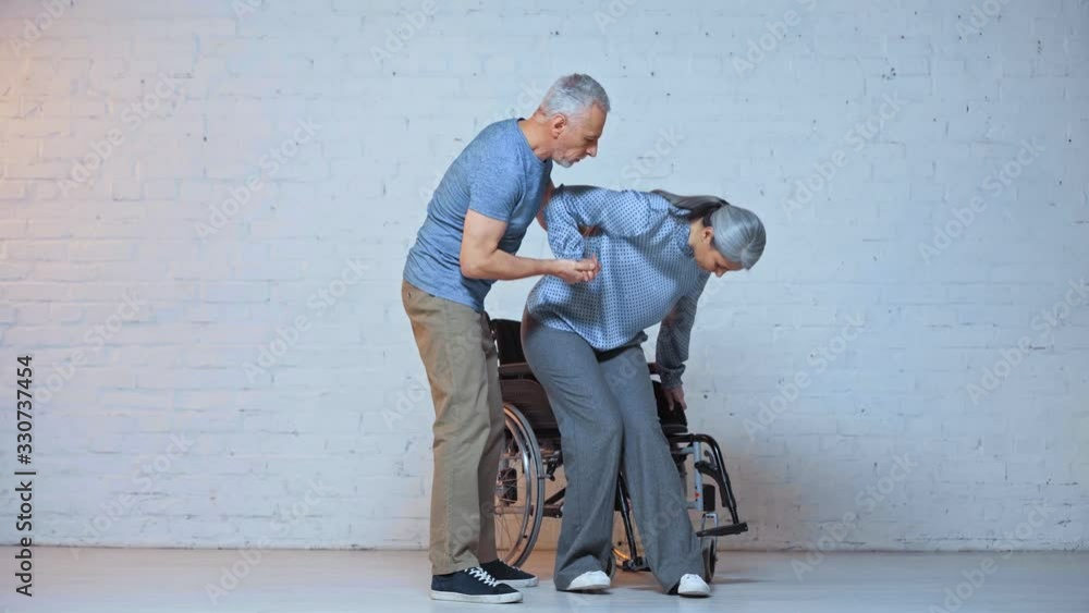 caring senior man helping asian wife near wheelchair caring senior man helping asian wife near wheelchair