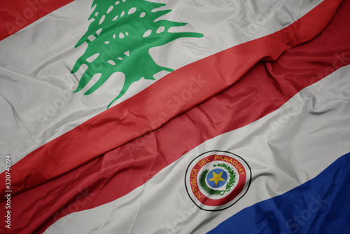 waving colorful flag of paraguay and national flag of lebanon. photo