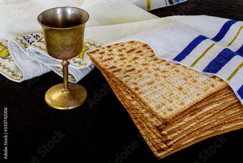 Passover matzoh jewish holiday bread, cup kosher wine over table.