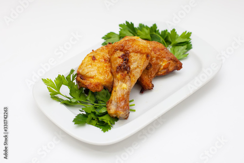 fried chicken legs with greens on a white plate