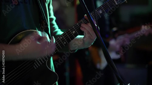 Male musician playing acoustic guitar with a pick, close-up, shooting in a nightclub / concert hall,slow motion