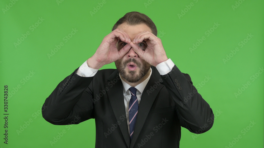 The Businessman looking from Hand Binoculars against Chroma Key The Businessman looking from Hand Binoculars against Chroma Key