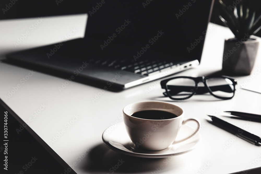 Business man using laptop computer with pen glasses and cup of hot coffee