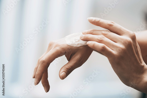 Woman applying moisturizing cream on hands