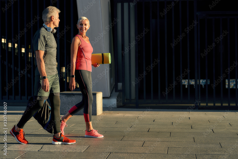 We love fitness. Side view of active middle-aged couple in sports