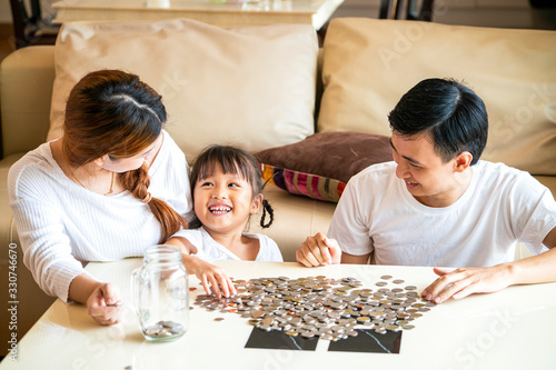 Asian family teaching their daughter saving money to piggy bank for her future education, Asian family concept