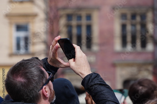 Hand of tourist holding mobile smartphone with black screen on the background of an old house, photographing sights or architecture. Journeys or Travel concepts and technology