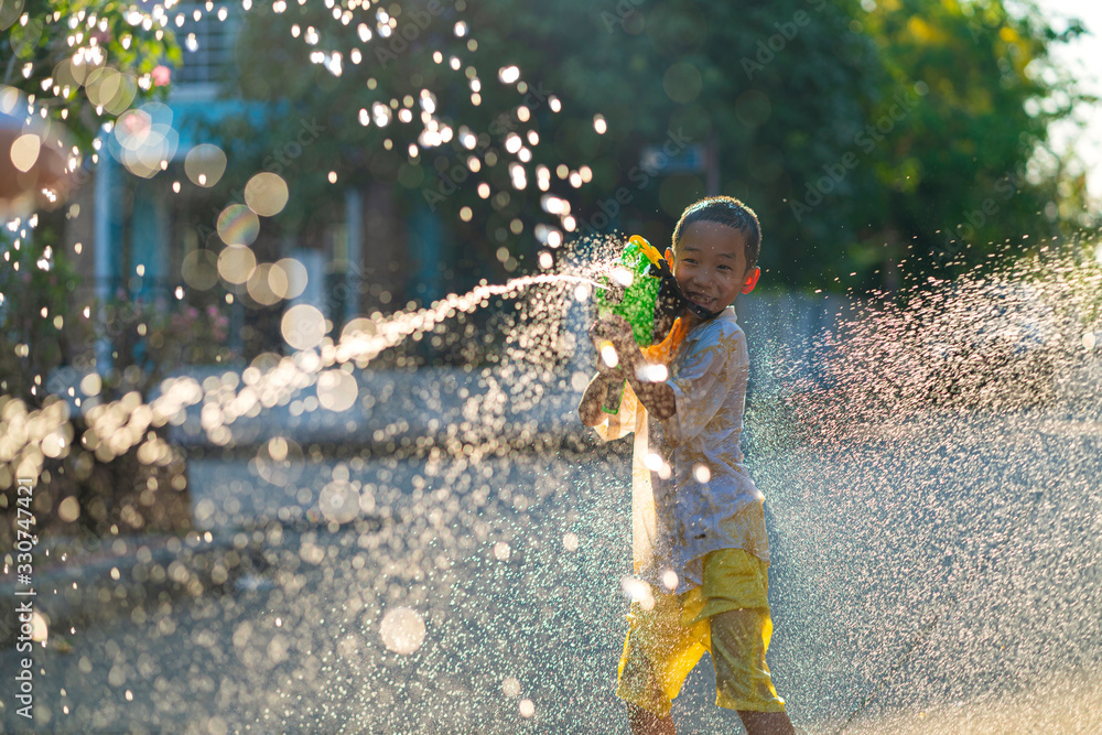 Asian children using water splash gun to their friend in very hot