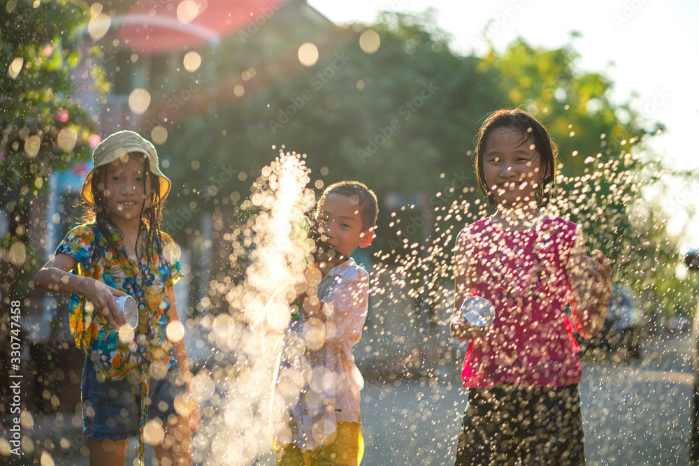 Asian children using water splash gun to their friend in very hot