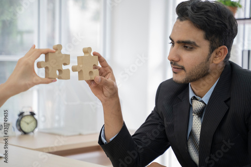 Slika na platnu An asian business people sitting at office desk, putting puzzle pieces together, finding solution