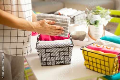 A woman folds her clothes and puts them in metal black baskets and boxes. Spring cleaning of closet. photo