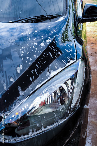 Washing black car with foam and soap.
