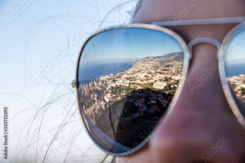 Mirroring sunglasses of a girl on madeira island with blue sky and the sea