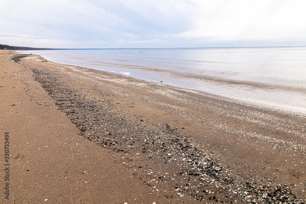 Obraz premium View of the sandy beach and the sea. Winter season. Cloudy, calm weather.