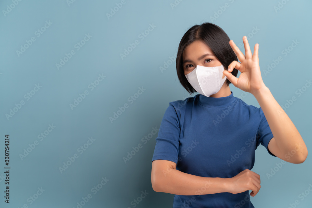 Portrait of asian woman wearing the hygienic mask isolated on blue background Portrait of asian woman wearing the hygienic mask isolated on blue background
