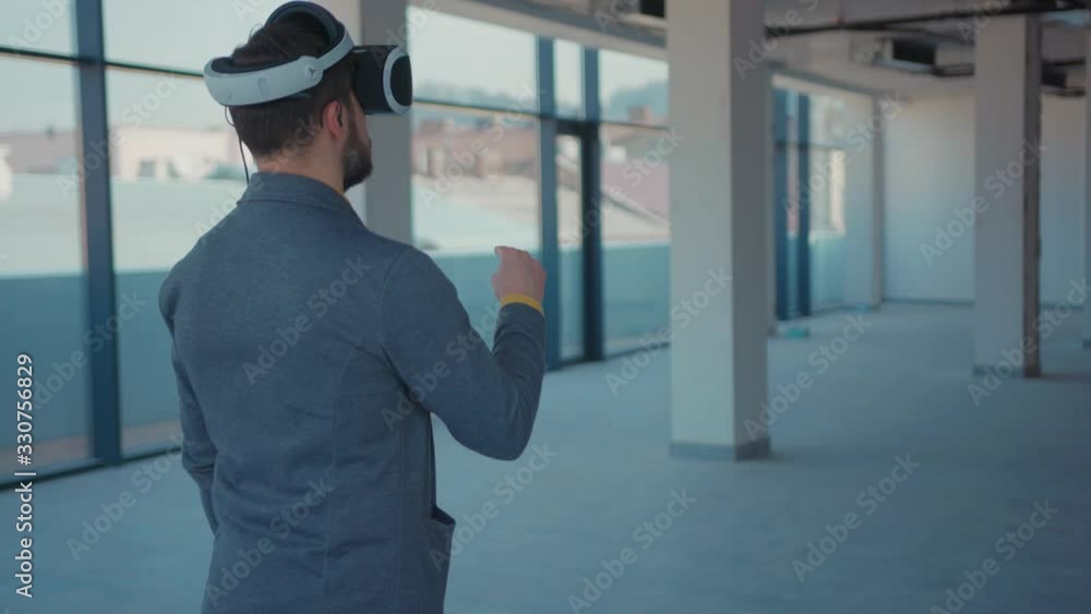 Man making gestures swipe when wearing virtual reality looks how the room will look like goggles empty building beard reaching technology looking entertainment gadget device tech game innovation close Man making gestures swipe when wearing virtual reality looks how the room will look like goggles empty building beard reaching technology looking entertainment gadget device tech game innovation close