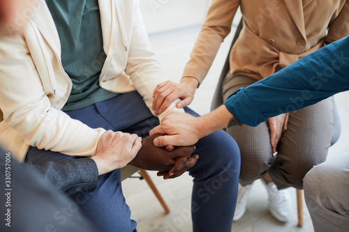 Fototapeta Naklejka Na Ścianę i Meble -  High angle closeup of people holding hands while comforting each other in psychology support group, copy space