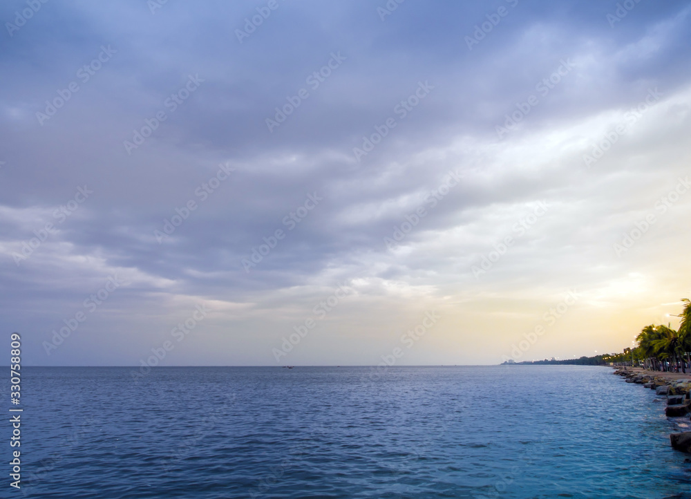 The sea is calm and the sky’s overcast with rain clouds in the morning of the coastal area