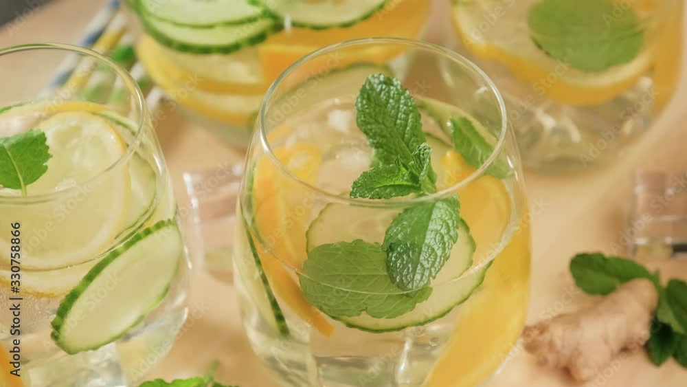 Rotating of glasses with summer healthy lemonade, cocktails of citrus infused water or mojitos, with lime lemon orange, ice and mint, diet detox beverages, on gray background. Rotating of glasses with summer healthy lemonade, cocktails of citrus infused water or mojitos, with lime lemon orange, ice and mint, diet detox beverages, on gray background.