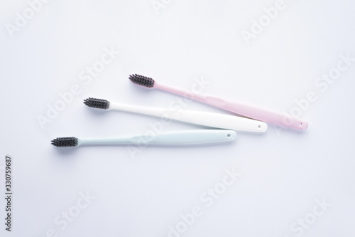 Flat lay composition multi-colored toothbrushes with black bristles on a white background.