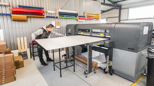 Technician operator works on large premium industrial printer plotter machine photo