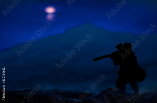 ancient warrior stranger vagabond person silhouette in fur cape with ax stay back to camera on a hill at phantom blue night nature atmospheric environment and looking on dark unfocused landscape