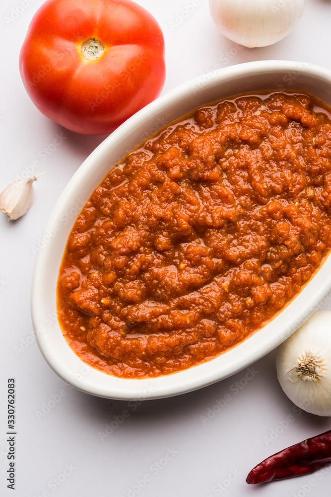 onion tomato masala or puree for indian gravy, served in a bowl with raw tamatar, pays and lehsun and red chilli, selective focus onion tomato masala or puree for indian gravy, served in a bowl with raw tamatar, pays and lehsun and red chilli, selective focus