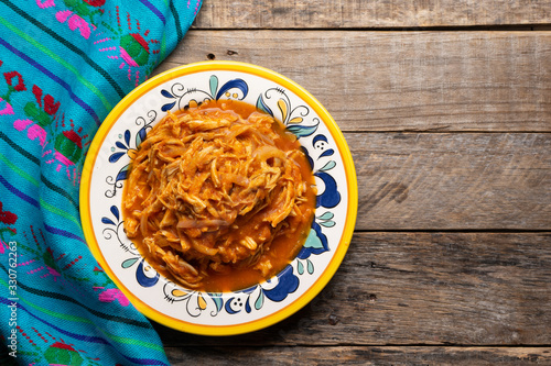 Mexican chicken tinga with chipotle sauce on wooden background