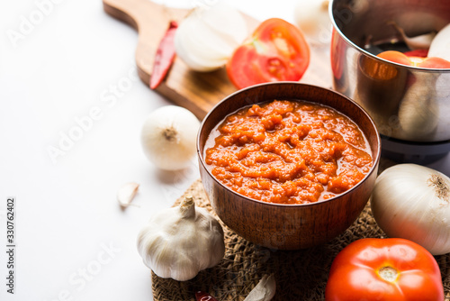 onion tomato masala or puree for indian gravy, served in a bowl with raw tamatar, pays and lehsun and red chilli, selective focus photo