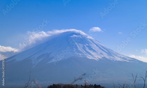 A beautiful full view of the fuji mountain with snow and clouds covering the top.