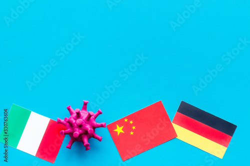 Concept of Corona virus Covid-19 with german, italian and chinease flags on blue background top-down photo