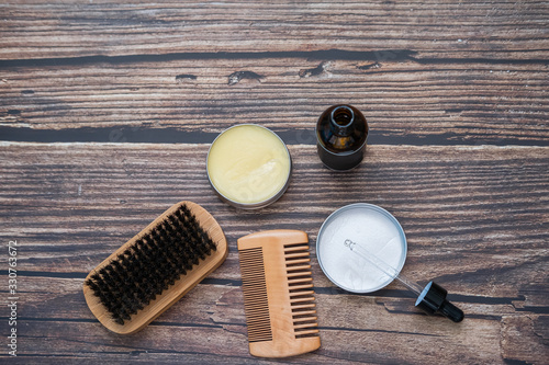Tools to take care of the beard. Wax, comb, brush and balm on wooden background. Top view. Flat lay. Copy space.