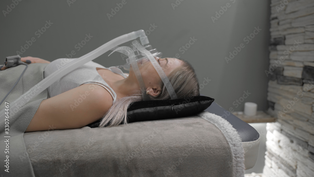 Girl lies on bed with artificial respiration mask - obrazy, fototapety, plakaty 