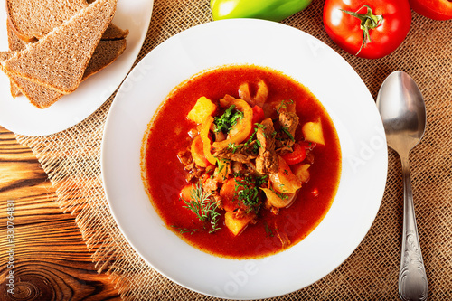 Hot beef hungarian  goulash soup with paprika, beef, potatoes, carrots, onion, pepper and herbs. Ingredients for dish.  Rustic background.  Top view.