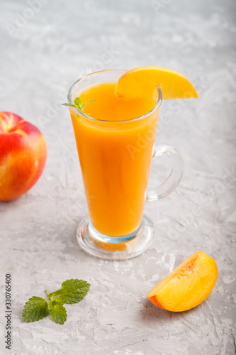 Glass of peach juice on a gray concrete background. Side view