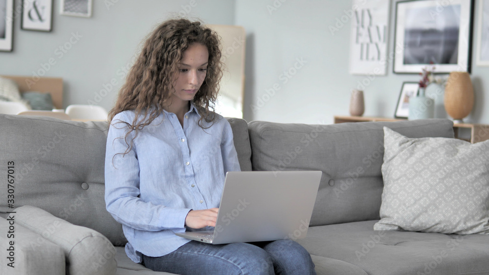 Curly Hair Woman Working On Laptop while Sitting on Couch Curly Hair Woman Working On Laptop while Sitting on Couch