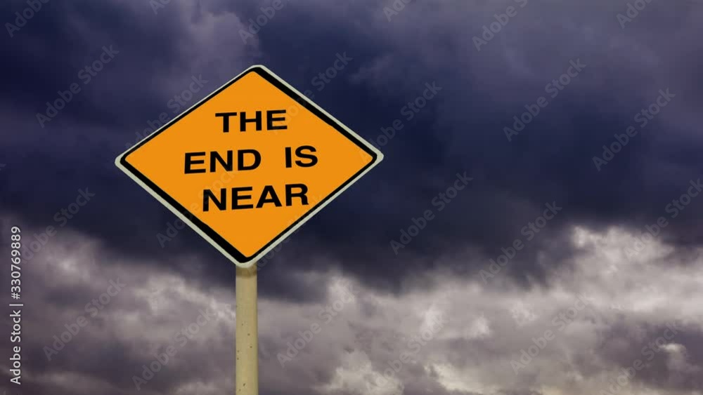 The end is near orange diamond shaped warning sign under gathering dark time lapse storm clouds. The end is near orange diamond shaped warning sign under gathering dark time lapse storm clouds.