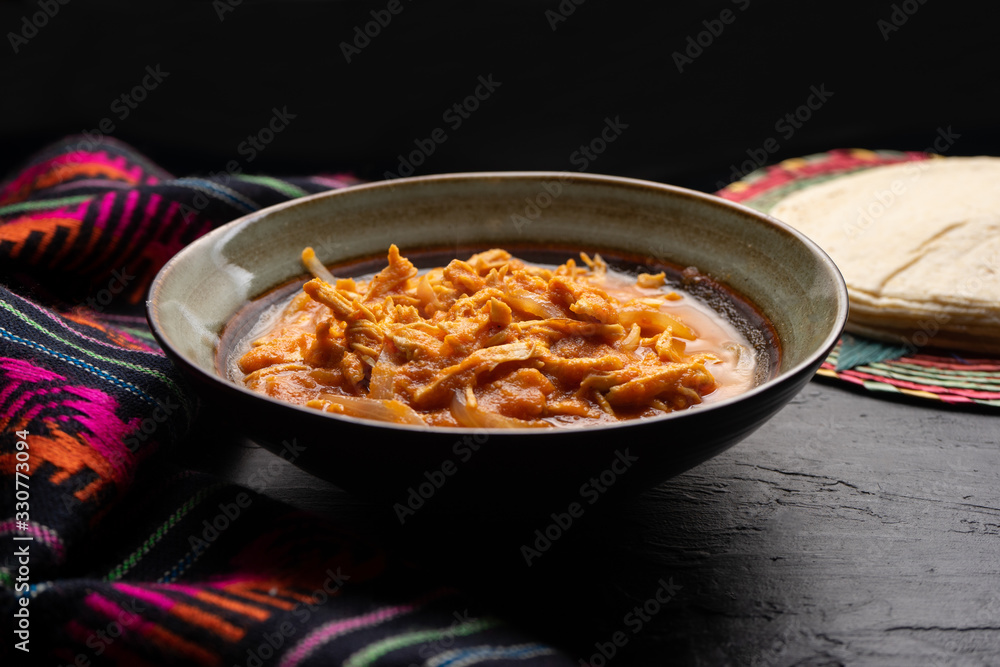 Mexican chicken tinga with chipotle sauce on dark background